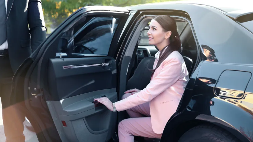 Femme en costume rose sortant d'une voiture